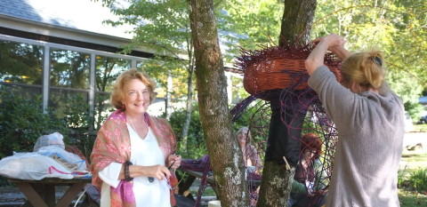 Lois Russell visits with Karen Gubitz as she works on a BaskeTree